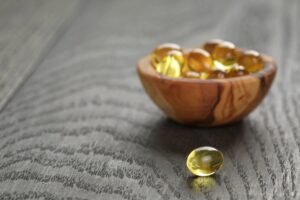 fish oil capsules in wood bowl on wooden table, copy space